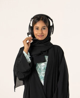 Entertainment and leisure using headphone technology, listening to music and audio, wearing audio headphones, a portrait of a young Arab Gulf Emirati woman wearing an abaya and hijab and headphones, enjoying listening to songs with gestures of joy and happiness, full-body, white background.