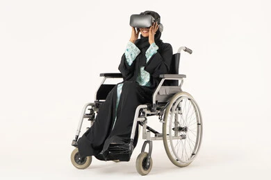 التطور التقني والتكنولوجي، متعة المشاهدة الترفيهية بتقنيات الواقع الافتراضي، الاندماج ومحاكاة العالم الخيالي، بورترية  لشابة عربيه خليجيه اماراتية من ذوى الاحتياجات الخاصة ترتدي العباءة و الحجاب ونظارات ثلاثية الأبعاد (الفي ار) تجلس على كرسي متحرك، خلفية بيضاء