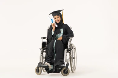 The importance of university education and the joy of achieving success, celebrating the completion of university studies, the feeling of happiness, pride, and self-confidence, the concept of diligence and excellence, a portrait of an Emirati Arab Gulf student with special needs wearing a dress and graduation cap sitting in a wheelchair holding her graduation certificate, looking at the camera with gestures of satisfaction and joy, white background.