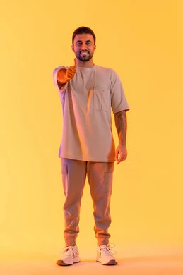 مفهوم الاتفاق والموافقه، الإشارة باصبع الإبهام نحو الأعلى تعابير القبول والفرح والسرور، التعبير عن الجودة الممتازة، بورتريه لرجل عربي خليجي اماراتي يرتدي االزي الكاجوال ينظر للكاميرا بإيماءات الرضا، مفهوم الاناقة و الاهتمام بالمظهر الخارجي, خلفية برتقاليه