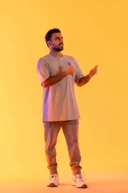 القيام بالمقابلات وطرح الأسئلة، غناء مقطع صوتي غنائي، بورتريه لرجل عربي خليجي إماراتي يرتدي الزي الكاجوال يمسك المايكروفون ويغني بحماس، إيماءات الإندماج والتفاعل، التواصل الفعال وتبادل الحوارات، الجسم بالطول الكامل، خلفية برتقالي .