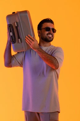 مشاعر السرور والفرح، التحضير قضاء رحلة صيفية ممتعة، القيام بالجولات الترفيهية، مفهوم السياحة في إجازة الصيف، بورتريه لرجل عربي خليجي اماراتي يرتدي الزي الكاجوال ونظارة شمسية يحمل على كتفه حقيبة الامتعة، السياحة في إجازة الصيف, خلفية برتقاليه