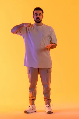 Looking at the camera with gestures of joy, standing upright and straight, lifting and holding something, a portrait of a smiling Emirati Gulf Arab man wearing casual attire pointing with his index finger, expressions of holding an item, the concept of masculinity and elegance, full-body image, orange background.