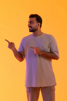 Clarification of a specific location, the concept of attractiveness and self-confidence, standing upright and straight, looking with gestures of joy, a portrait of a smiling Emirati Gulf Arab man wearing casual attire pointing with his hands to a specific place, the concept of masculinity and elegance, pointing to a specific goal, orange background.