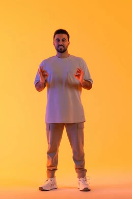 مفهوم الوسامة والثقة بالنفس، الوقوف باستقامة واعتدال, النظر بإيماءات السرور والراحة، بورتريه لرجل عربي خليجي اماراتي مبتسم يرتدي الزي الكاجوال يرفع يديه على شكل بيرفكت أو تمام، مفهوم الرجولة والاناقة، الإشارة إلى تحقيق هدف محدد، الجسم بالطول الكامل، خلفية برتقاليه