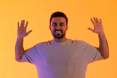 Protecting oneself from external harm, a Saudi young man raises his hands in gestures of stop and do not approach, a close-up portrait of an Emirati Arab man wearing casual attire standing cautiously with fear and awe, anxiety and caution and distancing from something, yellow background.