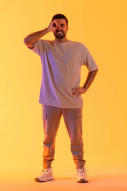 حب المغامرة والاستكشاف، التخطيط المستقبلي للأهداف والطموحات، بورتريه لشاب عربي خليجي  اماراتي يرتدي الزي الكاجوال يضع يده على عينه على شكل منظار، رجل سعودي يقوم برؤية الاشياء البعيدة، الجسم بالطول الكامل، خلفية صفراء