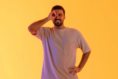 التخطيط المستقبلي للأهداف والطموحات، حب المغامرة والاستكشاف، بورتريه لشاب عربي خليجي  اماراتي يرتدي الزي الكاجوال يضع يده على عينه على شكل منظار، رجل سعودي يقوم برؤية الاشياء البعيدة، خلفية صفراء