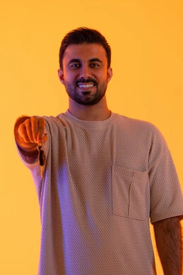 الحماس لامتلاك سيارة جديدة، استلام وتسليم المفاتيح، الحصول على رخصة القيادة، خدمه صف السيارات بالمواقف الخاصه، رجل سعودي ينظر إلى الكاميرا بتعابير السرور, بورتريه لشاب عربي خليجي اماراتي يرتدي الزي الكاجوال يمسك بيده مفتاح , الجسم بالطول الكامل، خلفية صفراء