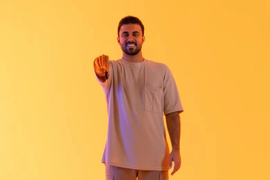 The excitement of owning a new car, receiving and handing over the keys, obtaining a driver's license, valet parking service, a Saudi man looking at the camera with expressions of joy, a portrait of a young Arab Gulf Emirati wearing casual attire holding a key in his hand, full-body, yellow background.