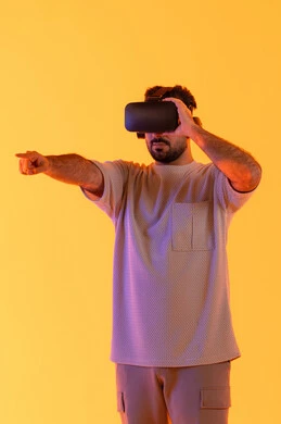 السعادة برؤية المشاهد الخيالية، الاشارة بإصبع السبابة إلى شيء ما، استخدام الأجهزة التقنية الحديثة، التفاعل والاندماج مع الواقع الافتراضي، بورتريه لشاب عربي خليجي إماراتي يرتدي الزي الكاجوال يضع نظارات الفي آر، رجل سعودي يقضي أوقات الفراغ بشكل ممتع، خلفية صفراء
