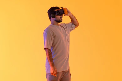 محاكاة العالم الخيالي، السعادة برؤية المشاهد الخيالية، استخدام الأجهزة التقنية الحديثة، التفاعل والاندماج مع الواقع الافتراضي، بورتريه لشاب عربي خليجي إماراتي يرتدي الزي الكاجوال يضع نظارات الفي آر، رجل سعودي يقضي أوقات الفراغ بشكل ممتع، خلفية صفراء