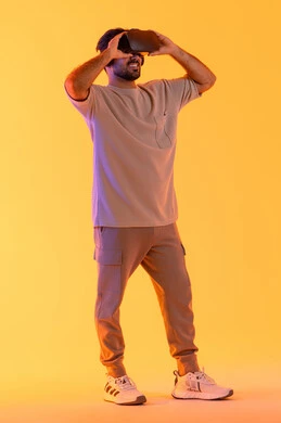التفاعل والاندماج مع الواقع الافتراضي، بورتريه لشاب عربي خليجي إماراتي يرتدي الزي الكاجوال يضع نظارات الفي آر، استخدام الأجهزة التقنية الحديثة والتكنولوجيا في رؤية المشاهد الخيالية، رجل سعودي يقضي أوقات الفراغ بشكل ممتع، الطول الكامل للجسم، خلفية صفراء