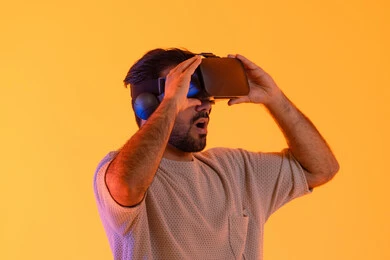 Joy and happiness in seeing imaginary scenes, using modern technological devices, interacting and merging with virtual reality, a close-up portrait of a young Arab Gulf Emirati man wearing casual attire and VR glasses, a Saudi man enjoying his leisure time, yellow background.