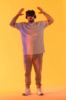 استخدام الأجهزة التقنية الحديثة والتكنولوجيا في رؤية المشاهد الخيالية، التفاعل والاندماج مع الواقع الافتراضي، بورتريه لشاب عربي خليجي إماراتي يرتدي الزي الكاجوال يضع نظارات الفي آر، رجل سعودي يقضي أوقات الفراغ بشكل ممتع، الطول الكامل للجسم، خلفية صفراء