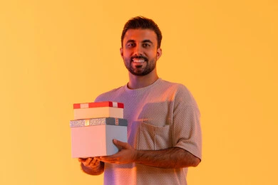Expressing love, appreciation, and respect, the concept of gratitude and thankfulness, giving gifts during holidays and special occasions, a Saudi man looking at the camera with gestures of joy and happiness, a close-up portrait of a young Emirati Arab man wearing casual attire holding a gift box in his hands, with a yellow background. Expressing love, appreciation, and respect, the concept of gratitude and thankfulness, giving gifts during holidays and special occasions, a Saudi man looking at the camera with gestures of joy and happiness, a close-up portrait of a young Emirati Arab man wearing casual attire holding a gift box in his hands, with a yellow background.