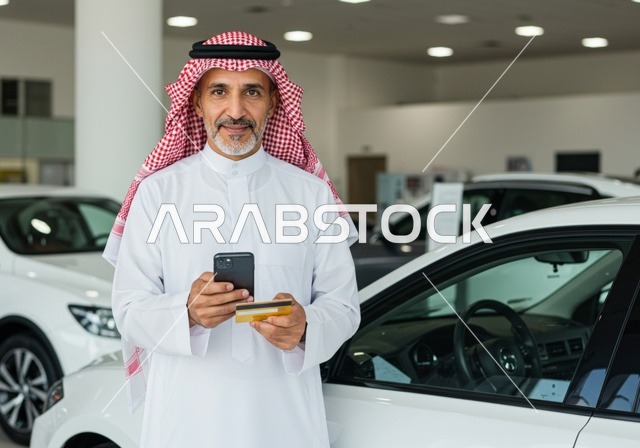 دفع حساب السيارة في مقهى راقي ، رجل عربي خليجي سعودي يرتدي الثوب والشماغ التقليدي يقوم بالدفع  بطريقة الكترونية بإستخدام بطاقة الإئتمان البنكية ، سهولة الدفع عبر بطاقة الصراف