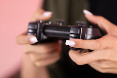 عصا التحكم لألعاب الفيديو البلايستيشن ، أجهزة تكنولوجية و الكترونية ، تقنيات و ألعاب، تصوير مقرب ليد امراه عربيه خليجيه اماراتية تقوم بقضاء وقت ممتع بالعب ، خلفية وردية