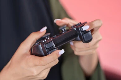 عصا التحكم لألعاب الفيديو البلايستيشن ، أجهزة تكنولوجية و الكترونية ، تقنيات و ألعاب، تصوير مقرب ليد امراه عربيه خليجيه اماراتية تقوم بقضاء وقت ممتع بالعب ، خلفية وردية