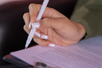 مفهوم كتابه وتدوين الملاحظات، بورتريه مقرب ليد امراة عربية خليجية اماراتية تمسك بيدها قلم تقوم بالكتابة على نوت، استخدام الورق الأبيض في تسجيل الملاحظات والمعلومات المهمة، خلفية وردية