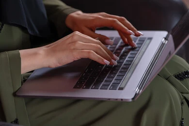 صناعة المحتويات النصية ، تصوير مقرب ليد امراة عربيه خليجيه اماراتية تستخدم الحاسوب المحمول ، الكتابة من خلال لوحة المفاتيح ، ادخال البيانات، التسويق والترويج للمواقع الالكترونية، القيام بالاعمال الادارية ،التعليم الالكتروني، خلفية وردية