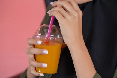 الاستمتاع بتناول المشروبات المفيدة اللذيذة، محاولة التخفيف من حرارة الصيف بالمشروب المنعش، بورترية  مقرب ليد امراة عربية خليجية  اماراتية  تستمع بشرب العصير الطبيعي البارد، خلفية وردية