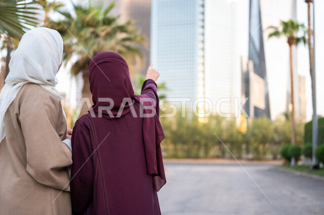 سيدتان عربيتان خليجيتان سعوديتان تشيران الى ابراج مدينة الملك عبد الله المالية كافد في مدينة الرياض في المملكة العربية السعودية ، اطلالة على الابراج وناطحات السحاب ،جولة سياحية في المدينة المالية ، قضاء وقت ممتع