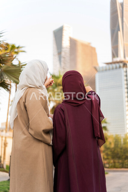 سيدتان عربيتان خليجيتان سعوديتان تشيران الى ابراج مدينة الملك عبد الله المالية كافد في مدينة الرياض في المملكة العربية السعودية ، اطلالة على الابراج وناطحات السحاب ،جولة سياحية في المدينة المالية ، قضاء وقت ممتع