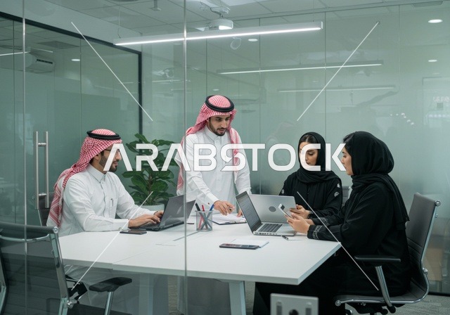 استخدام الحاسب والتقنية في مجال الاعمال، بيئة العمل المريحة في الشركات السعودية، الحوار و النقاش بين الزملاء، تبادل الخبرات والمعلومات لتحقيق الاهداف, موظفين عربيين خليجيين سعوديين يجلسون على طاولة الاجتماع داخل مقر الشركة