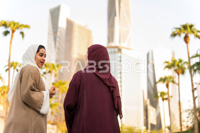 سيدتان عربيتان خليجيتان سعوديتان تتحدثان مع بعضهما البعض ، التجول في مدينة الملك عبد الله المالية كافد في مدينة الرياض في المملكة العربية السعودية ،قضاء وقت ممتع في المدينة المالية