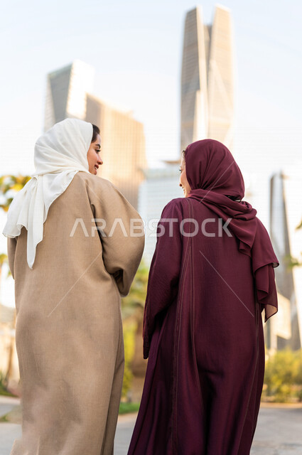 سيدتان عربيتان خليجيتان سعوديتان تتحدثان مع بعضهما البعض ، التجول في مدينة الملك عبد الله المالية كافد في مدينة الرياض في المملكة العربية السعودية ،قضاء وقت ممتع في المدينة المالية