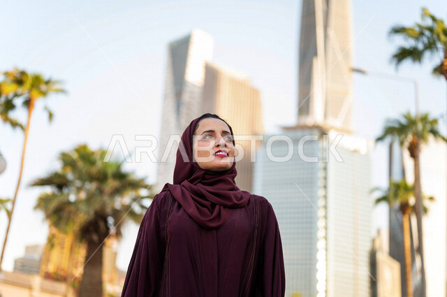 سيدة عربية خليجية سعودية تقف امام ابراج مدينة الملك عبد الله المالية كافد في مدينة الرياض في المملكة العربية السعودية ، قضاء وقت ممتع ، جولة سياحية في المدينة المالية