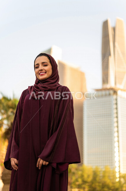 سيدة عربية خليجية سعودية تقف امام ابراج مدينة الملك عبد الله المالية كافد في مدينة الرياض في المملكة العربية السعودية ، قضاء وقت ممتع ، جولة سياحية في المدينة المالية