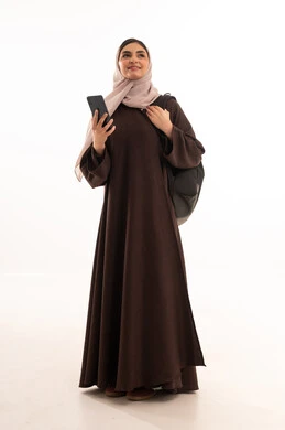 استخدام مواقع الابحاث العلمية على الانترنت, استخدام الأجهزة التقنية الحديثة والمتطورة, بورتريه لامرأة عربية خليجية سعودية محجبة ترتدي العباءة وتحمل حقيبة الظهر تعمل على الجهاز المحمول, شابة سعودية تقوم بإنجاز المهام, الجسم بالطول الكامل، خلفية بيضاء