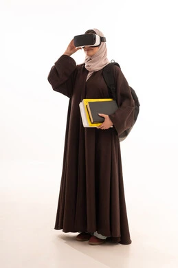 محاكاة العالم الخيالي، مفهوم التفاعل والاندماج، دمج التقنيات الحديثة بالتعلم، بورتريه من الجانب لطالبة جامعية عربية خليجية سعودية محجبة ترتدي حقيبة الظهر تضع نظارة الفي ار ثلاثية الأبعاد تحمل مجموعة من الكتب تشير بيدها لمكان ما، صورة لكامل الجسم، خلفية بيضاء