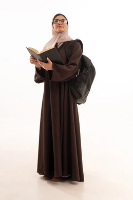 التعليم والدراسة في المملكة، حب الثقافة والاستطلاع، بورتريه طالبة عربية خليجية سعودية ترتدي الحجاب والعباءة تحمل مجموعة كتب تنظر إلى الكتاب بإيماءات التركيز والتأمل، قضاء وقت الفراغ بالتعلم والتثقف الذاتي, تنمية مهارة القراءة للطلاب, خلفية بيضاء