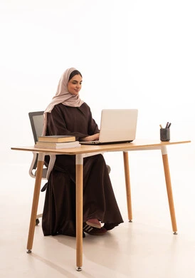 الأجهزة التقنية الحديثة بالتعلم,، متابعة المحاضرات عن طريق منصات التعلم، بورتريه لطالبه عربيه خليجيه سعودية ترتدي الحجاب والعباءة تجلس على الطاولة المكتبيه ، بنت سعودية تقوم بحل الواجبات وتلقي المحاضرات المدرسيه عن بعد عبر التابلت، خلفية بيضاء