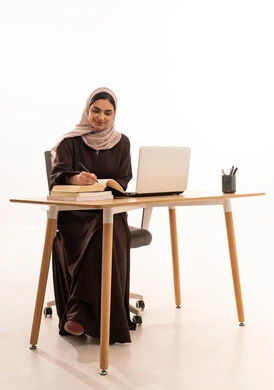 تدوين وكتابة الملاحظات خلال المحاضرة، الأجهزة التقنية الحديثة بالتعلم,، متابعة المحاضرات عن طريق منصات التعلم، بورتريه لطالبه عربيه خليجيه سعودية ترتدي الحجاب والعباءة تجلس على الطاولة المكتبيه ، حل الواجبات وتلقي المحاضرات المدرسيه عن بعد عبر التابلت، خلفية بيضاء