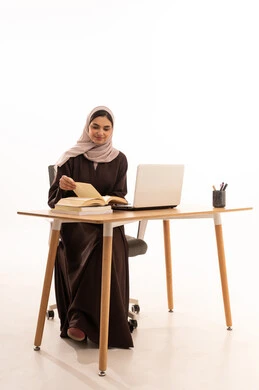 تقليب الصفحات خلال المحاضرة، المحاضرات الجامعية عن بعد عبر الحاسب، الأجهزة التقنية الحديثة بالتعلم,، متابعة المحاضرات عن طريق منصات التعلم، بورتريه مقرب لطالبه عربيه خليجيه سعودية ترتدي الحجاب والعباءة تجلس على الطاولة المكتبيه ، خلفية بيضاء