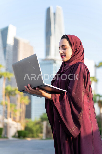 سيدة عربية خليجية سعودية تستخدم الحاسوب المحمول في مدينة الملك عبد الله المالية كافد في مدينة الرياض في المملكة العربية السعودية، مشروع عمل ، دراسة ميدانية ، العمل عن بعد