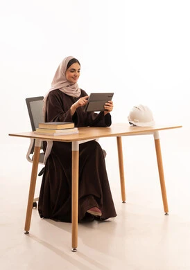 العمل على الجهاز اللوحي ، طالبة هندسة معمارية تحضر المحاضرات الجامعية عن بعد عبر التابلت، الأجهزة التقنية الحديثة بالتعلم,، بورتريه مقرب لطالبه عربيه خليجيه سعودية ترتدي الحجاب والعباءة تجلس على الطاولة المكتبيه ، خلفية بيضاء