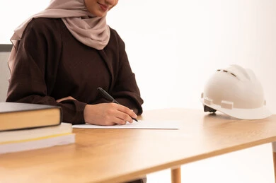 تدوين وكتابة ذكريات الرحلة التعليمية ، طالبة هندسة معمارية تحضر المحاضرات الجامعية عن بعد عبر التابلت، الأجهزة التقنية الحديثة بالتعلم,، بورتريه مقرب لطالبه عربيه خليجيه سعودية ترتدي الحجاب والعباءة تجلس على الطاولة المكتبيه ، خلفية بيضاء