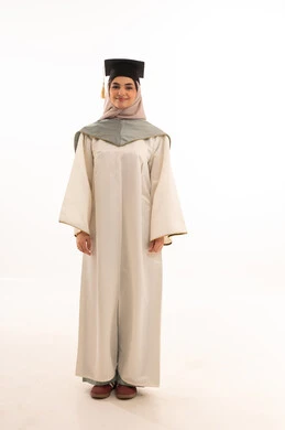 النجاح والتفوق والتخرج من الجامعة، إيماءات السعادة بالوصول الى الحلم، مناسبة واحتفال جامعي، الاحتفال بإنهاء الدراسة الجامعية، النظر الى الكاميرا بايماءات الفخر، بورتريه لخريجة عربية خليجية سعودية محجبة ترتدي زي التخرج والقبعة ، خلفية بيضاء