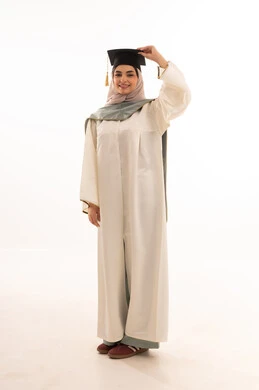 مناسبة واحتفال جامعي، إيماءات السعادة بالوصول الى الحلم، النجاح والتفوق والتخرج من الجامعة، الاحتفال بإنهاء الدراسة الجامعية، النظر الى الكاميرا بايماءات الفخر، بورتريه لخريجة عربية خليجية سعودية محجبة ترتدي زي التخرج والقبعة ، خلفية بيضاء