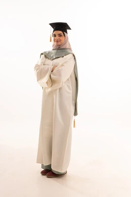 The celebration of completing university studies is an occasion and a university celebration, gestures of happiness at reaching the dream, success, excellence, and graduation from the university, looking at the camera with gestures of pride, a portrait of a veiled Saudi Gulf Arab graduate wearing graduation attire and cap, with a white background.