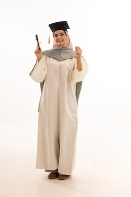 رفع قبضت اليد بايماءات الفرح، الاحتفال بإنهاء الدراسة الجامعية، مناسبة واحتفال جامعي، إيماءات السعادة بالوصول الى الحلم، النجاح والتفوق والتخرج من الجامعة، بورتريه لخريجة عربية خليجية سعودية محجبة ترتدي زي التخرج والقبعة وتحمل شهادة التخرج ، خلفية بيضاء