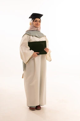 مشاعر السرور والسعادة بتحقيق حلم النجاح, الاحتفال بإنهاء الدراسة الجامعية، مناسبة واحتفال جامعي، إيماءات السعادة بالوصول الى الحلم، النجاح والتفوق والتخرج من الجامعة، بورتريه لخريجة عربية خليجية سعودية محجبة ترتدي زي التخرج والقبعة وتحمل شهادة التخرج ، خلفية بيضاء