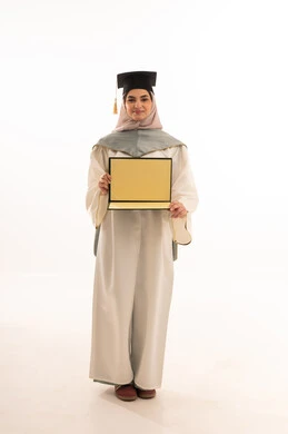 إيماءات السعادة بالوصول الى الحلم، النجاح والتفوق والتخرج من الجامعة، مناسبة واحتفال جامعي، الاحتفال بإنهاء الدراسة الجامعية، النظر الى الكاميرا بايماءات الفخر، بورتريه لخريجة عربية خليجية سعودية محجبة ترتدي زي التخرج والقبعة تحمل بيدها الشهادة، خلفية بيضاء