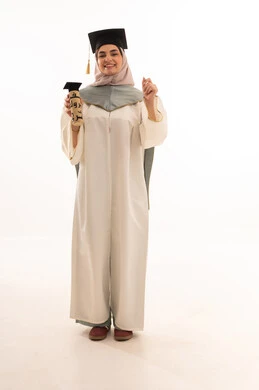 مناسبة واحتفال جامعي، إيماءات السعادة بالوصول الى الحلم، النجاح والتفوق والتخرج من الجامعة، الاحتفال بإنهاء الدراسة الجامعية، النظر الى الكاميرا بايماءات الفخر، بورتريه لخريجة عربية خليجية سعودية محجبة ترتدي زي التخرج والقبعة تحمل بيدها الشهادة، خلفية بيضاء