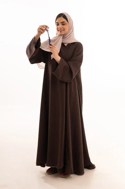 التسويق لمنتجات ومستحضرات التجميل, استخدام المساحيق التجميلية, مفهوم التزين والتجمل,  التسويق لمستحضرات ومنتجات التجميل, الاهتمام والعناية بالمظهر الخارجي,  بورتريه لامرأة عربية خليجية سعودية محجبة ترتدي العباءة السوداء تستعمل فرشاة المسكارة, خلفية بيضاء